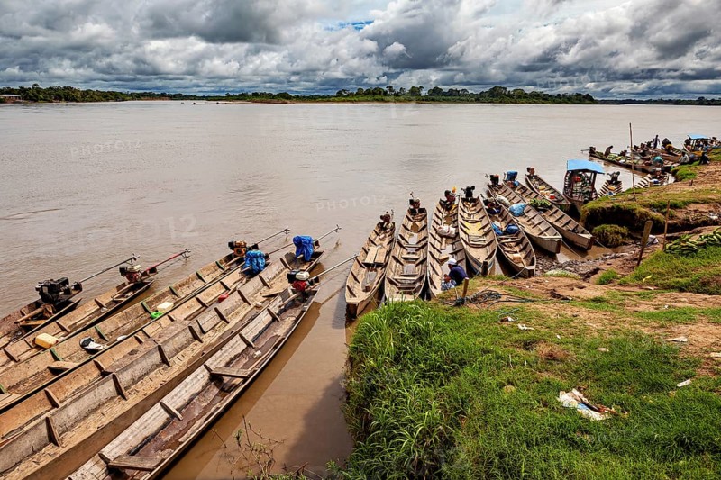 Wooden boats lie on the riverbank under a cloudy sky surrounded by lush greenery, longboat on a river near Rurrenabaque in the Amazon jungle in Bolivia