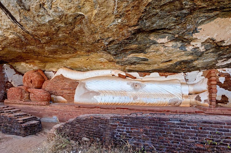 Reclining Buddha embedded in a rock wall, made of sandstone, peaceful and meditative atmosphere, The sleeping Buddha on Pidurangala rock near Sigiriya in Sri Lanka