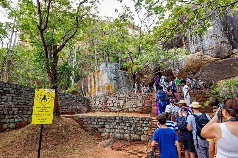 Group of people on a hiking trail next to rocks and trees, tourist environment, tourists at the temples and rocks of Lion Rock near Sigiriya in Sri Lanka
