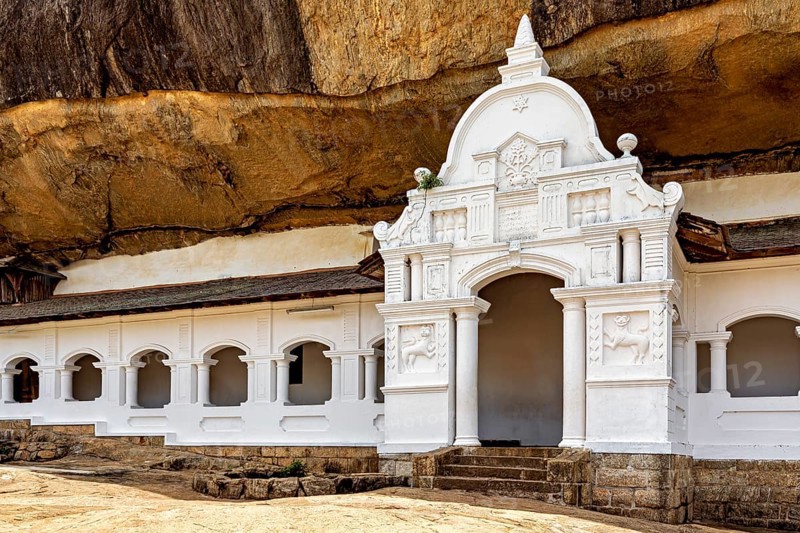 Historic cave monastery with white façade nestled in a rocky landscape, The cave temples of Dambulla in Sri Lanka