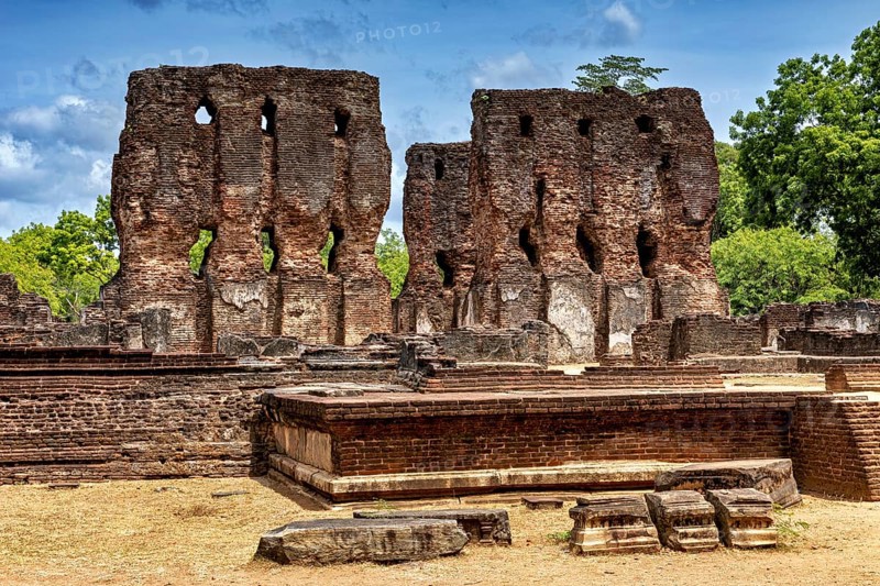 Brick ruins rising up against the sky surrounded by green foliage and crumbling architecture, The temples of Polonnaruwa in Sri Lanka