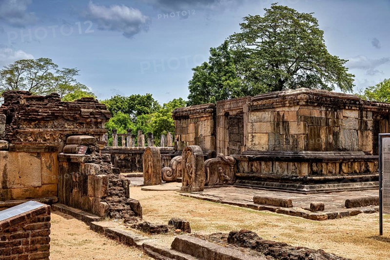 Old stone buildings in a ruined site with trees and blue sky in the background, The temples of Polonnaruwa in Sri Lanka