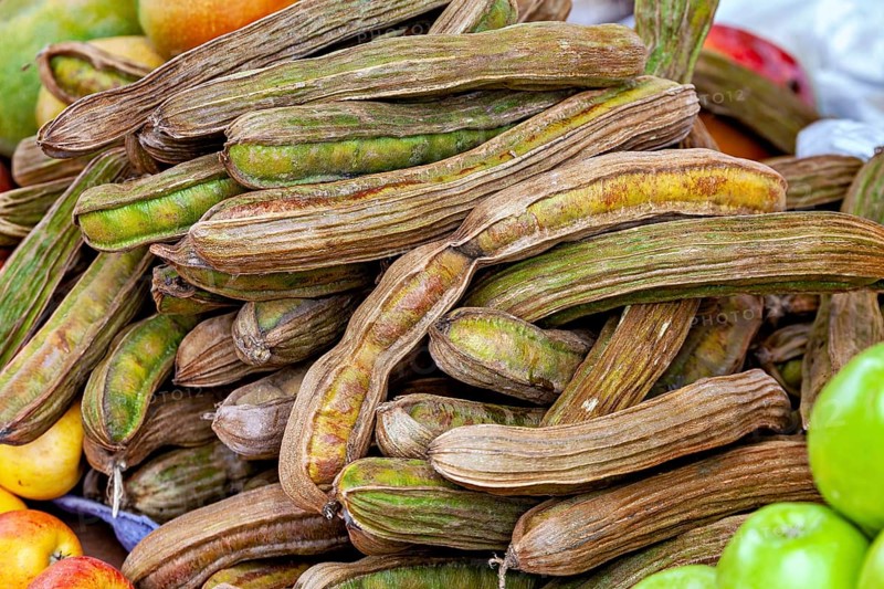 A pile of dried beans surrounded by various fresh fruits in rich colors, The fruits of the ice cream bean tree (Inga edulis or Inga feuilleei)