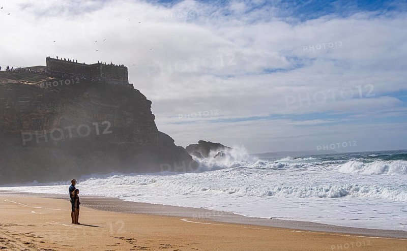 Tourists watch the waves of the Atlantic on the rocky plateau of Sito, also known as Forte São Miguel, a surfing paradise with monster waves in the months of November to February, Nazaré, Portugal