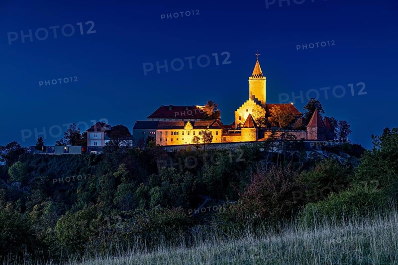 A castle at dusk, illuminated and picturesquely situated on a hill, in contrast to a clear blue sky, The Leuchtenburg near Kahla in the Saale Holzlandkreis district in Thuringia