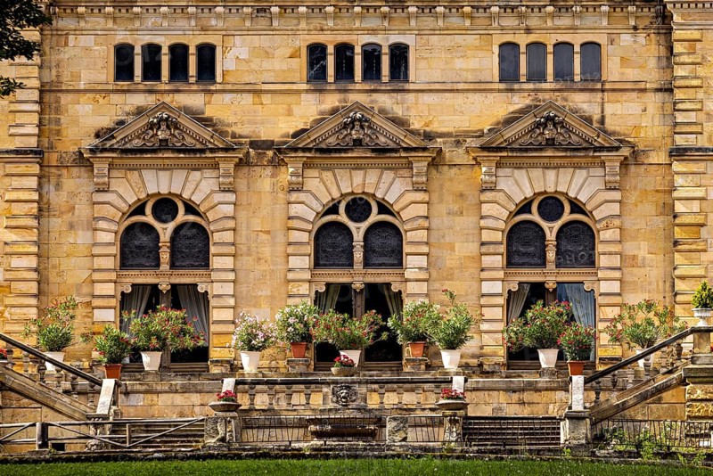 Detail of the castle façade with lush flowers in pots in front of large windows, The Hummelshain hunting lodge in Thuringia
