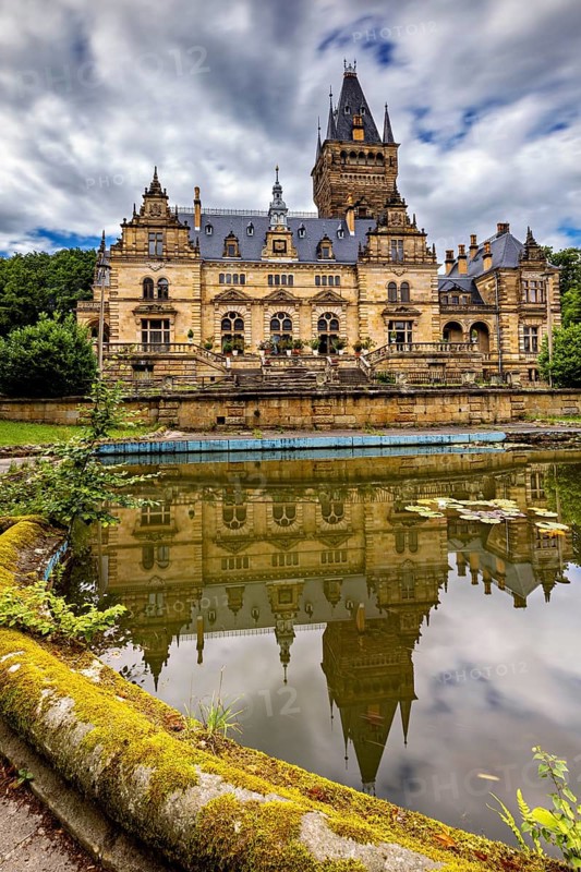 Impressive castle reflected in a quiet pond, cloudy sky above, The Hummelshain hunting lodge in Thuringia