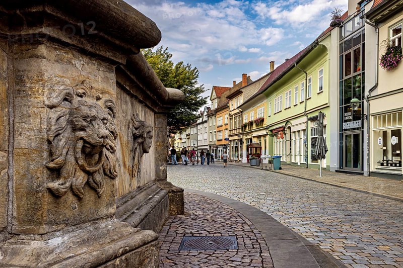 Urban street with lion head sculpture and historic architecture, animated by people, The old town of Arnstadt in Thuringia