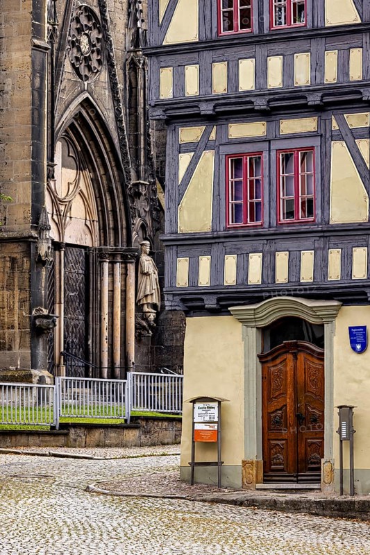 Detailed view of a church portal next to a half-timbered house, paved street in front of it, the old town of Arnstadt in Thuringia