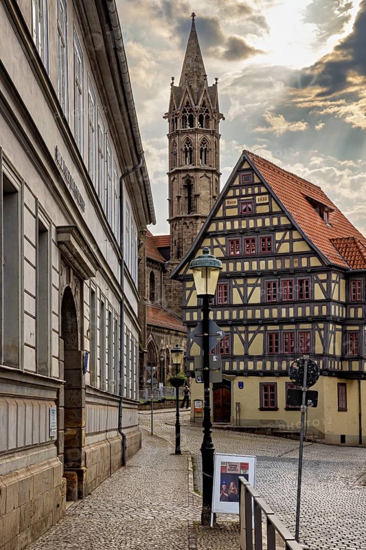 Alley with a view of a half-timbered house and a church tower, under a cloudy sky, the old town of Arnstadt in Thuringia