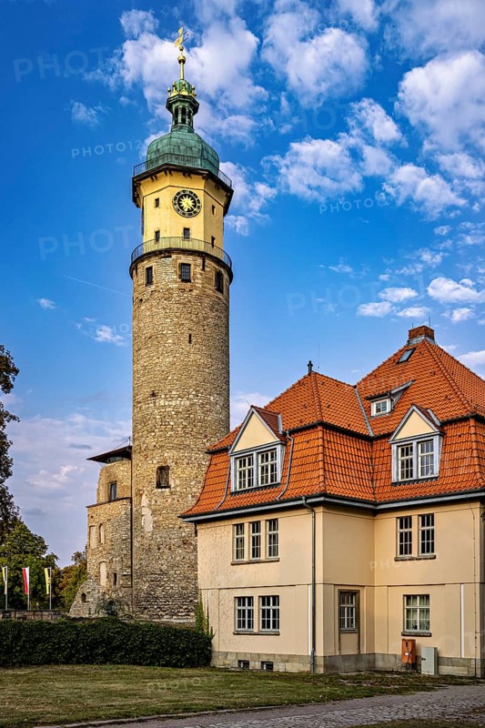 Large tower with clock and house with red roofs against cloudy sky, The Niedeck Ruins in Arnstadt Thuringia
