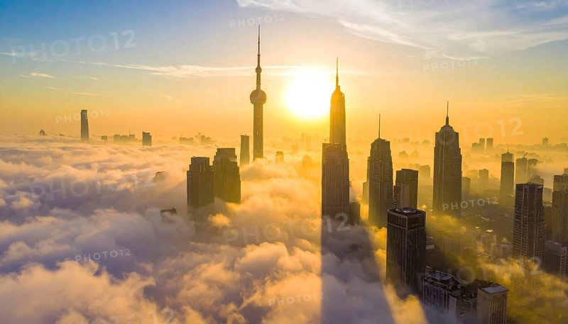 City scape emerging from a dense enveloping fog in sunrise and skyscrapers piercing the haze, big metropolis with skyline, mist on ground, blue sky, city in an aerial view, AI generated