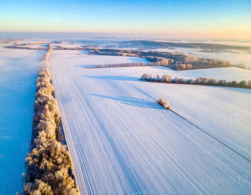 Bird Eye Perspective of Frost Covered Farmland. Seasonal Agricultural Scenery, winter and autumn scene, blue sky with golden light at sunrise, AI generated