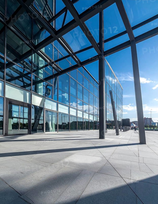 Modern architectural framework with glass and steel structure, glass facade with a greed of steel arrows, blue sky with a soft golden light of a sunrise, AI generated