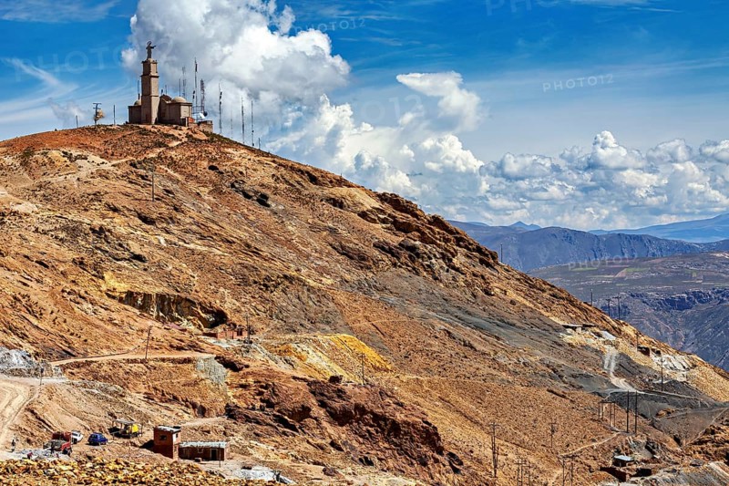 Rough mountain terrain with sparse vegetation and a transmission mast on the summit under a cloudy sky: the silver mines of the Cerro Rico silver mountain near Potosi in Bolivia