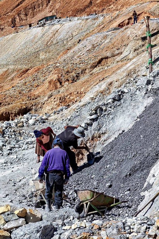 Workers bend on a rocky slope while loading gravel into wheelbarrows, The silver mines of Potosi Bolivia
