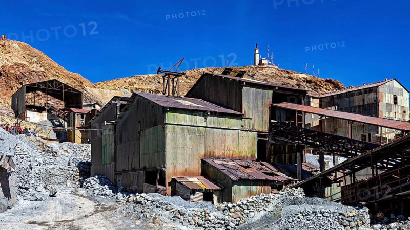 Weathered metal industrial buildings on a mountainside under a clear blue sky, The silver mines of Potosi Bolivia