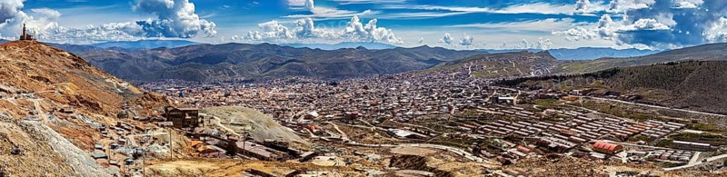 Expansive panorama of an urban landscape embedded in mountainous surroundings under a blue sky, view from Silver Mountain Cerro Rico to Potosi in Bolivia