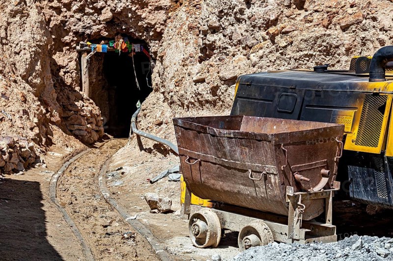 A mine car and a machine near the entrance of a rocky mine, The silver mines of the Cerro Rico silver mountain near Potosi in Bolivia