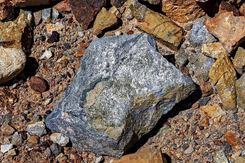 A large, grey rock on a soil of pebbles and earth, the silver ore from the Cerro Rico silver mountain near Potosi in Bolivia