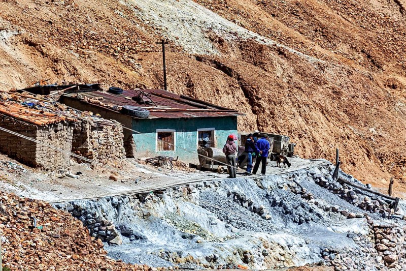 Miners in front of a house with wheelbarrows in a rocky landscape with railings, The silver mines of Potosi Bolivia