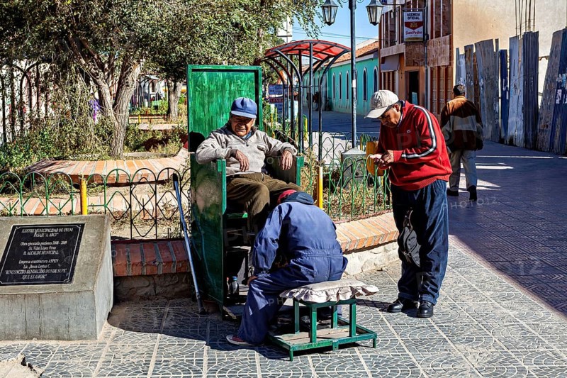 Relaxed street scene in the marketplace with men shining shoes and interacting socially, show shiners in the town of Uyuni in the Salar de Uyuni in Bolivia