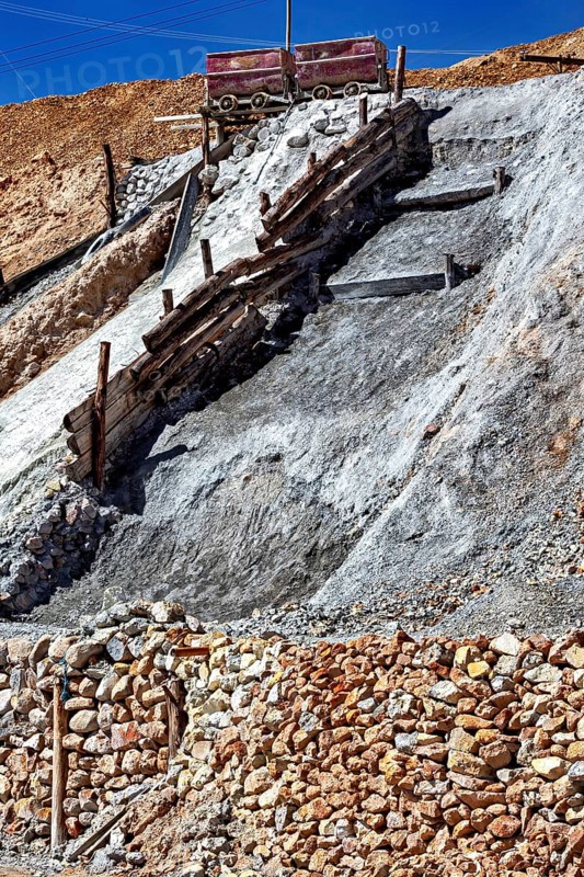 A lonely mine car stands on a rocky slope, surrounded by staggered layers of rock and wooden beams, mining lorry at the Cerro Rico silver mountain near Potosi Bolivia