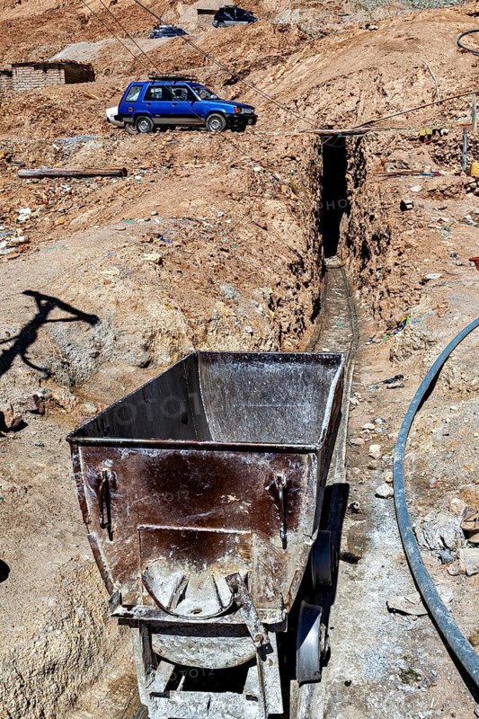 An old mining wagon stands next to a trench in an arid landscape, The silver mines of Potosi Bolivia