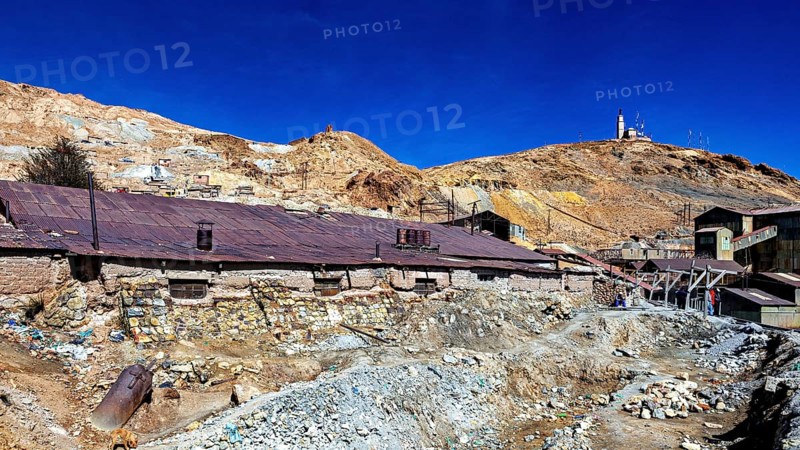 Old, dilapidated mining structures in front of a dry hill under a clear sky, The silver mines of Potosi Bolivia
