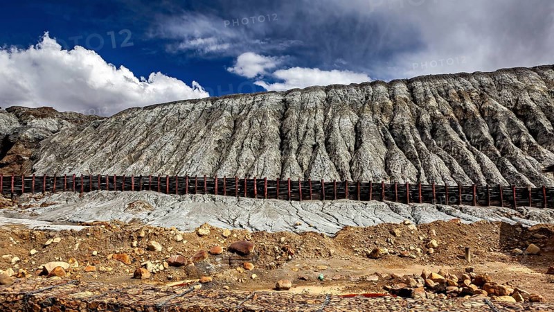 Steep rock faces in a barren desert landscape with clouds in the sky, spoil heap of the silver mines in Potosi Bolivia