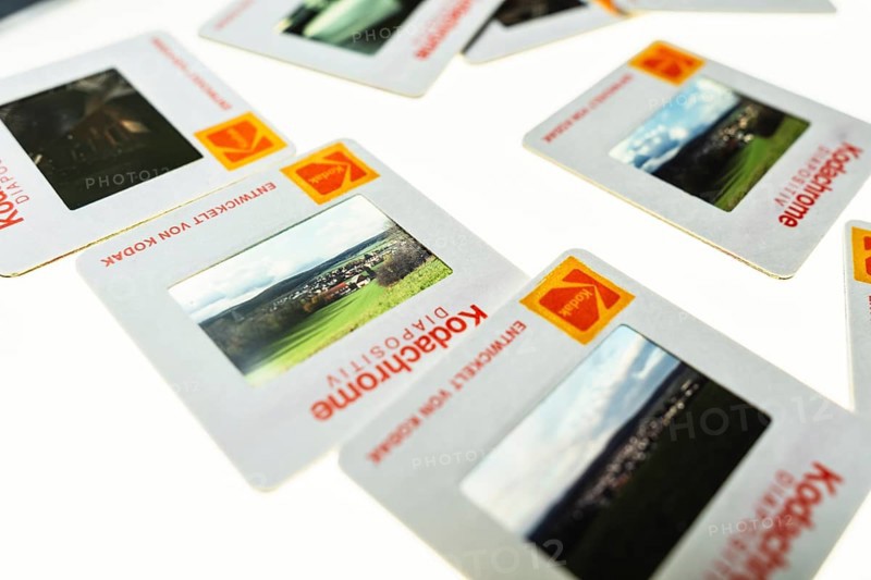 Many framed Kodachrome slides on a light table with magnifying glass, top shot