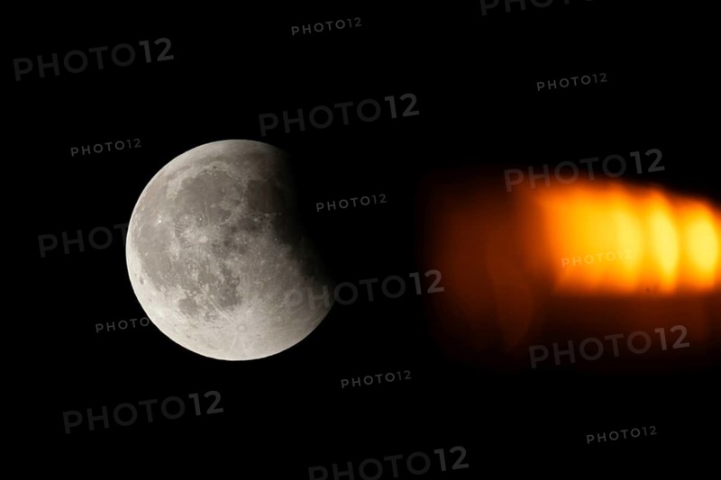 After a total lunar eclipse, the moon appears shortly after its rise in the evening sky as a so-called blood moon in front of it then begins to emerge from the Earth's umbra, Frankfurt am Main, Hesse, Germany