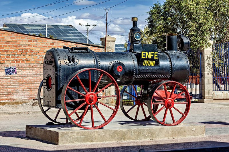 Old steam engine with red wheels stands on a pedestal in the open air in Bolivia, Old historic steam locomotive in Uyuni in Bolivia