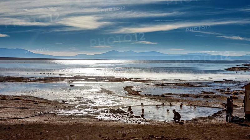 Landscape with hot springs, people and sweeping views of the lake and mountains, The thermal springs of Polques in Bolivia