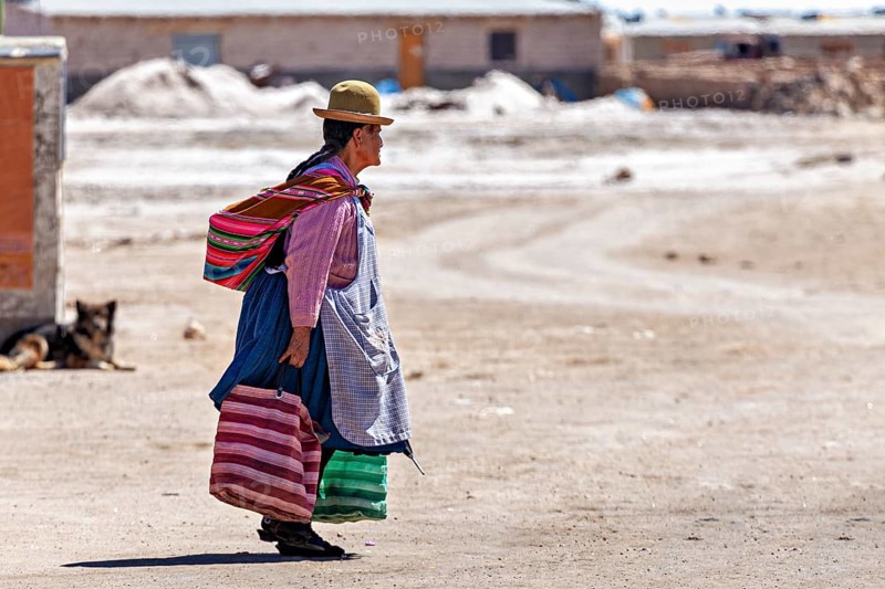 Man in traditional dress walks along a dusty road in a desert landscape, Traditional woman in a village in the Salar de Uyuni in Bolivia