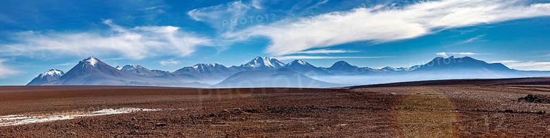 Long mountain range under a clear, cloudy sky in a vast landscape, The landscape with the volcanoes on the Altiplano in Bolivia