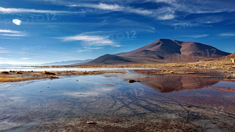Majestic mountains reflected in calm waters under clear skies, The thermal springs of Polques in Bolivia