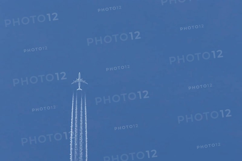 Airbus A340-300 jet aircraft of Lufthansa airlines in flight in a blue sky with vapour trails or contrails behind, England, United Kingdom