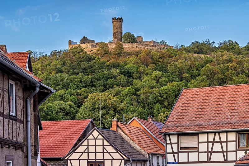 A quiet village scene with half-timbered houses and a castle on a hill, the ruins of Mühlburg Castle, one of the Drei Gleichen near Erfurt in Thuringia