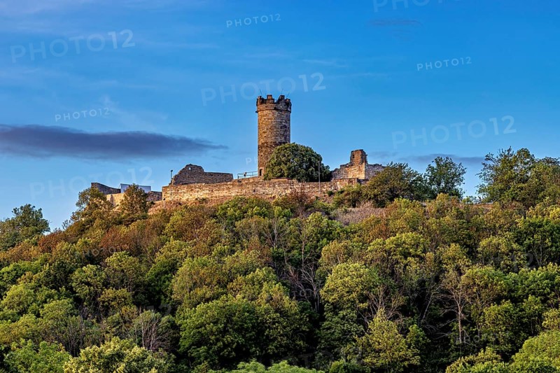 A castle with a tower on a wooded hill under a blue sky, the Mühlburg ruins one of the Drei Gleichen near Erfurt in Thuringia