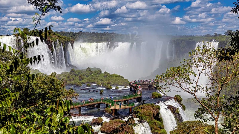 Dense vegetation surrounds a platform from which visitors can view the waterfalls, The Iguazu Falls between Argentina and Brazil