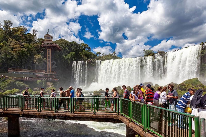 Tourists on a bridge watch the impressive waterfalls in the background, The Iguazu Falls between Argentina and Brazil
