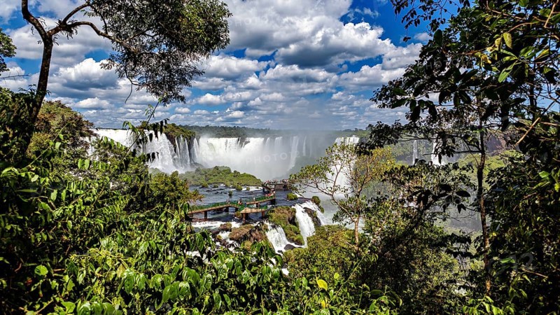 Lush green surroundings, waterfalls in the background, viewpoint with visitors, The Iguazu Falls between Argentina and Brazil