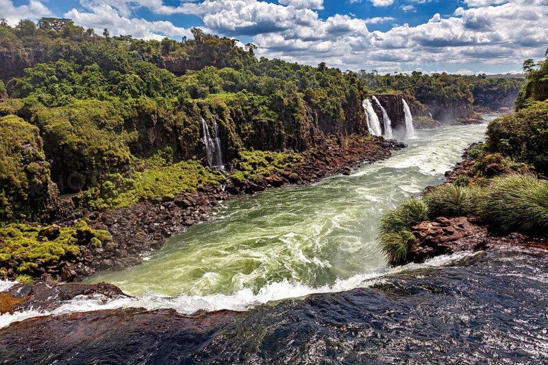 A wide river crosses a rocky gorge surrounded by green vegetation, The Iguazu Falls between Argentina and Brazil