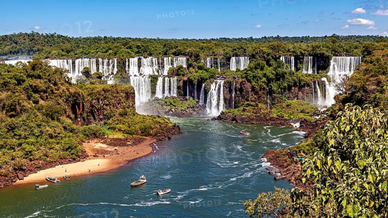 River course to the waterfalls, lined with forest and small boats, The waterfalls of Iguazu between Argentina and Brazil