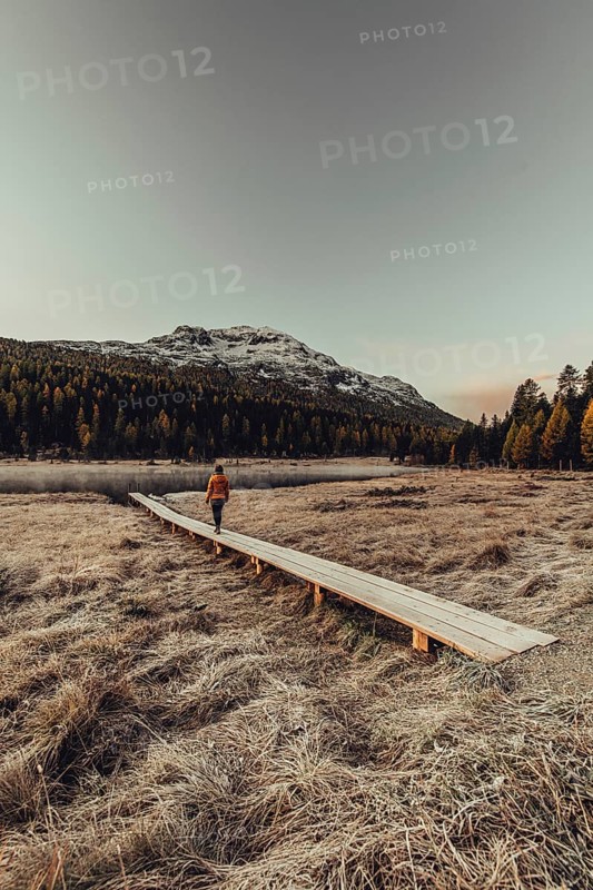Young woman at Lake Staz near Sankt Moritz in the Engadine in Switzerland. Morning atmosphere with fog in autumn. Reflection of water