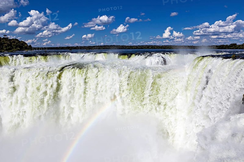 Spectacular waterfall with rainbow and spray under a cloudy sky, The Iguazu Falls between Argentina and Brazil