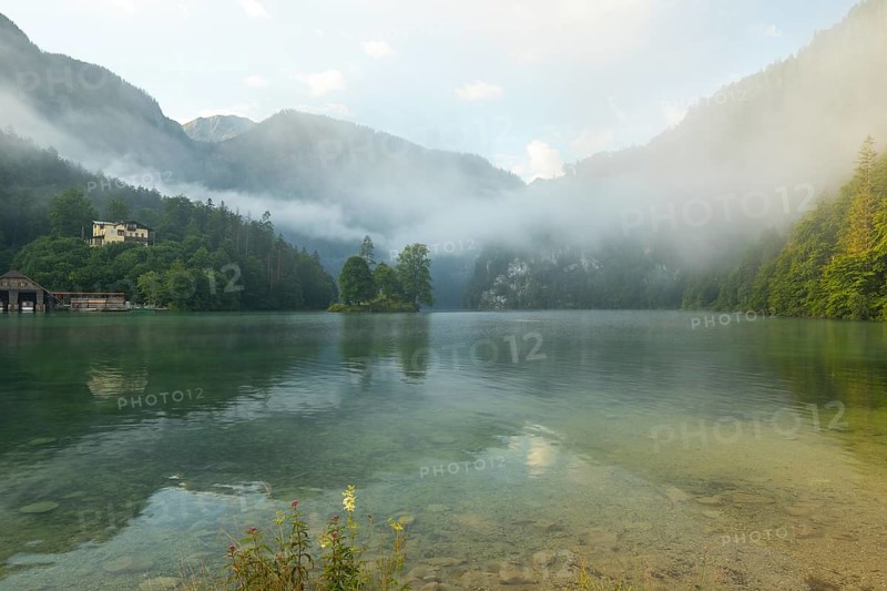 Mystical morning at Königssee in Schönau with boathouses and Christlieger. Sunrise and beautiful wafts of mist over the Königssee in the basin