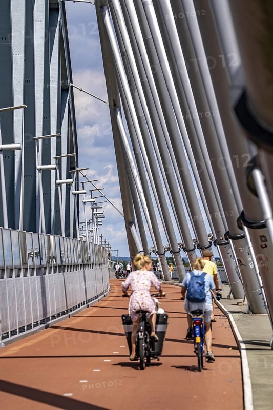Cycle and pedestrian bridge Snelbinder Brug, over the river Waal near Nijmegen, was added to the existing railway bridge, fast cycle path connection from the city centre of Nijmegen and the new housing estates in the Waalsprong district, Netherlands