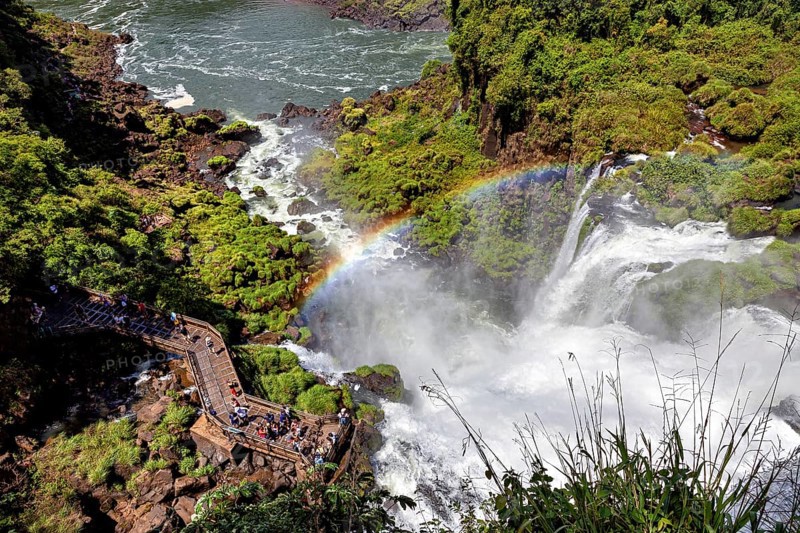 Viewing platform with visitors over a waterfall and rainbow, The Iguazu Falls between Argentina and Brazil